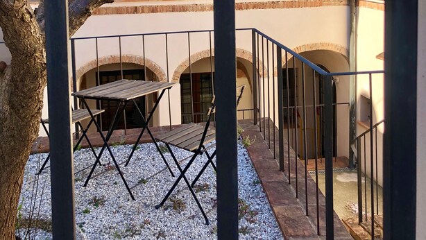 Une cour avec une pergola, une table et des chaises, et un arbre.