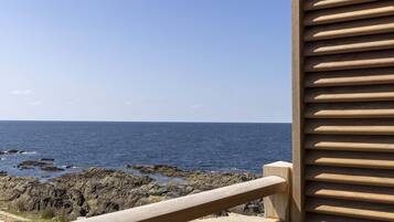 A view of the ocean from a balcony with a wooden railing.