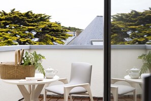 A balcony with a wicker basket, two white chairs, a small table, and a white teapot. - Hôtel Les Vikings (Le Croisic)