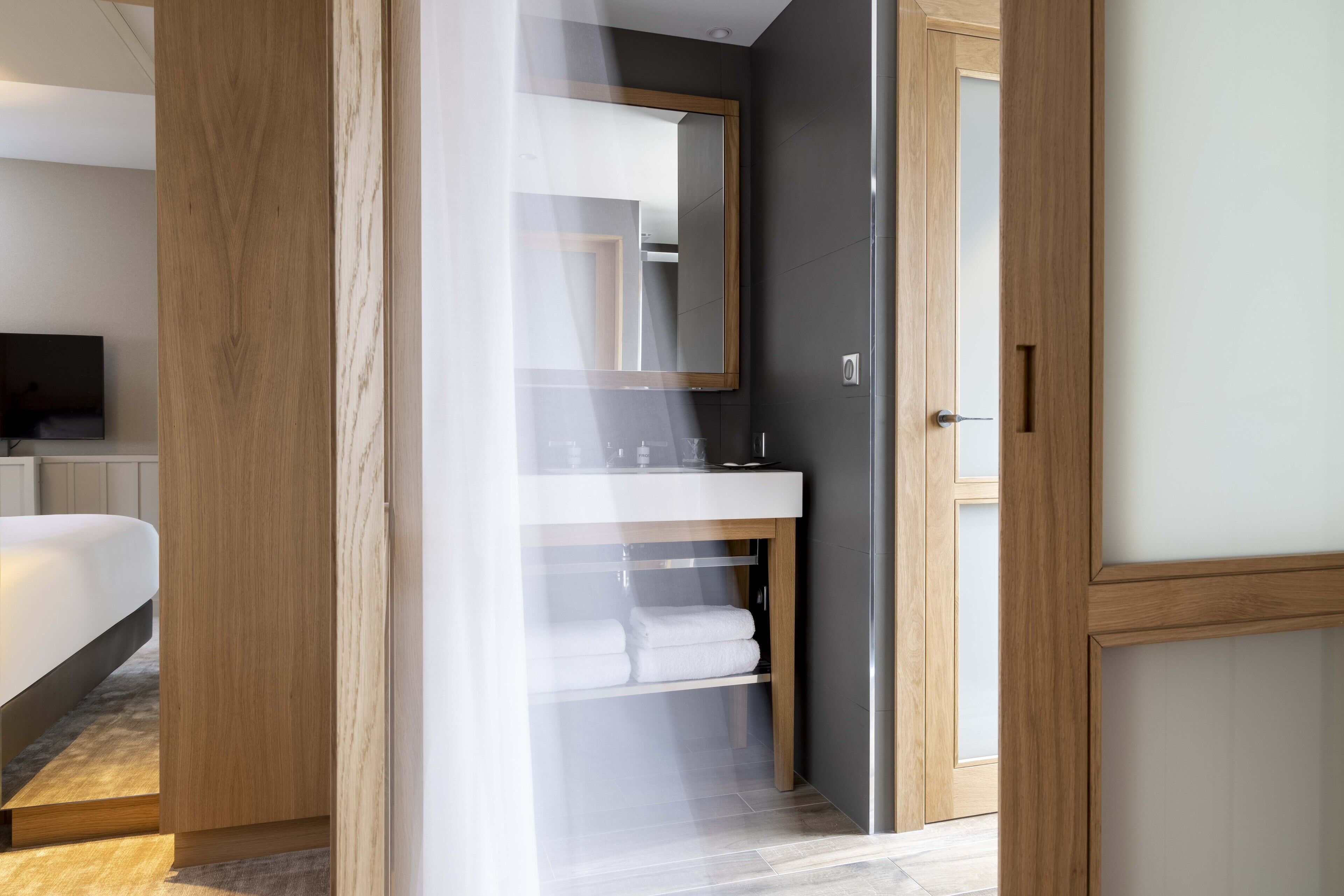 Un baño moderno con tocador de madera, un espejo grande y un lavabo blanco.