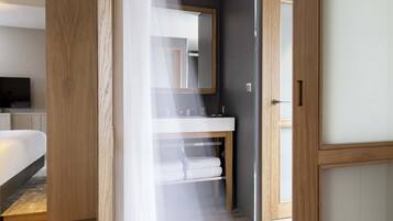 Un baño moderno con tocador de madera, un espejo grande y un lavabo blanco.