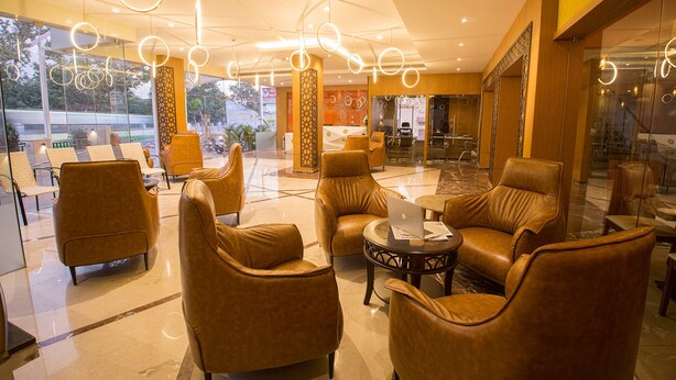 A lobby with leather chairs, a laptop on a table, and circular ceiling lights. - Samudra Mysore (Mysore)