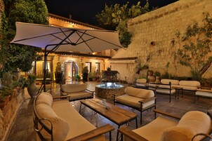 Un patio al aire libre con mobiliario, una chimenea y un muro de piedra.