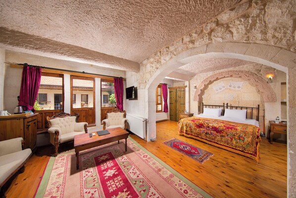 Ein Zimmer mit einem großen Bett, zwei Sesseln, einem Holztisch und einem Fernseher.