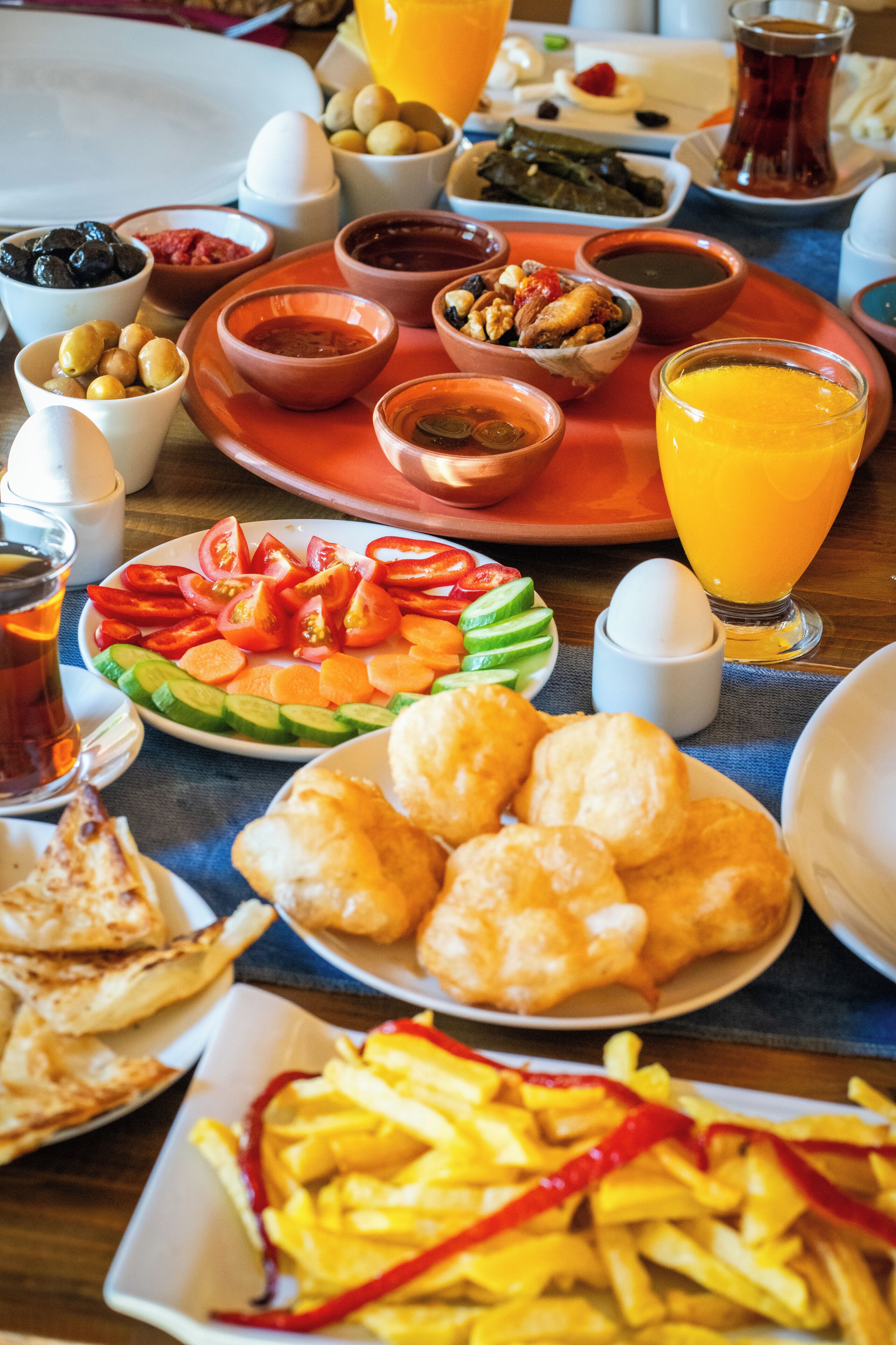 A table with various dishes including bread, vegetables, and a glass of orange juice.