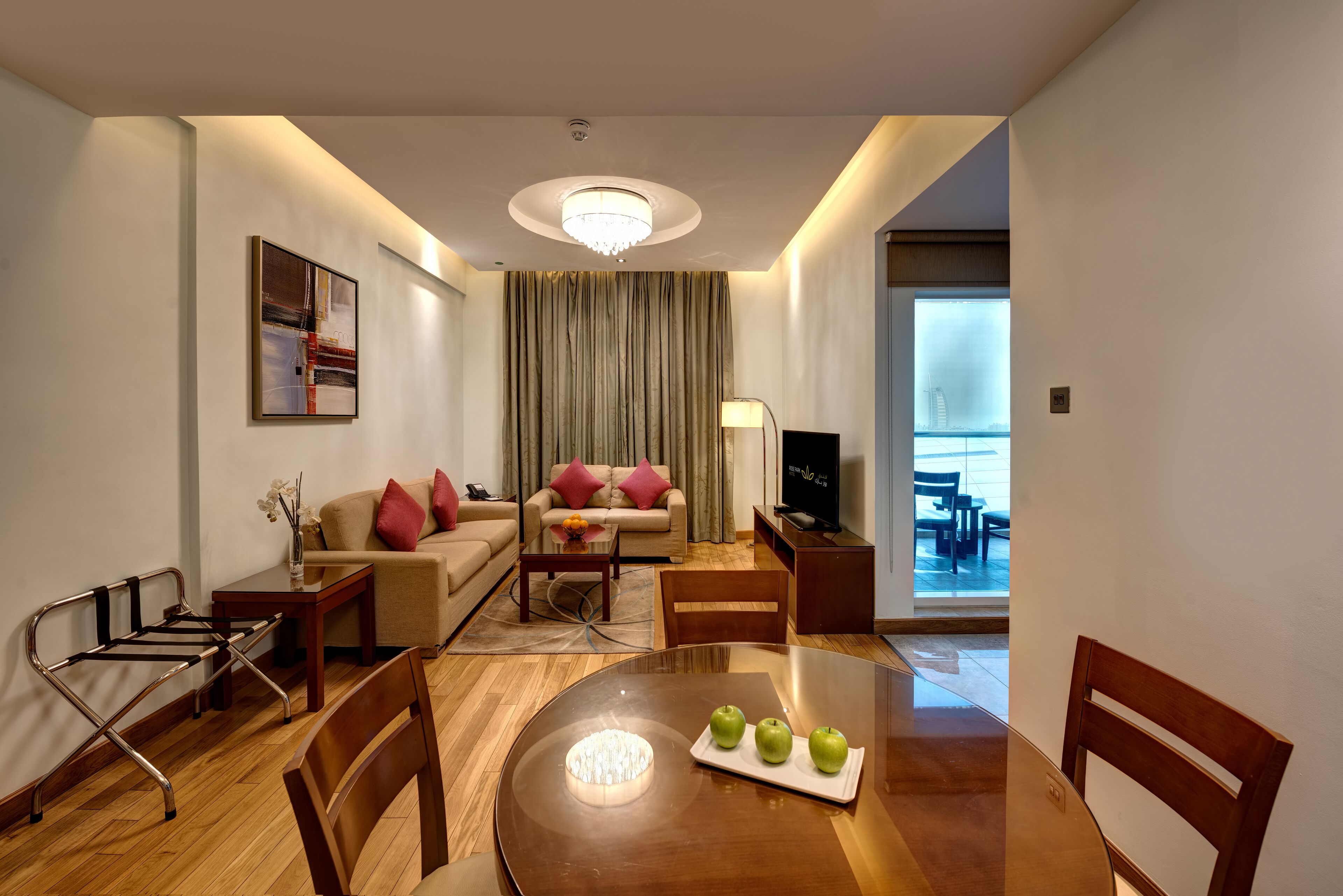 A modern hotel room with a dining table, chairs, a sofa, and a TV.