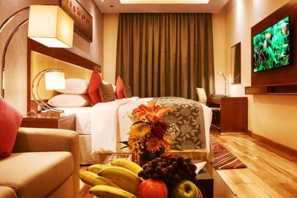 Een hotelkamer met een bed, een televisie, een bureau en een stoel.