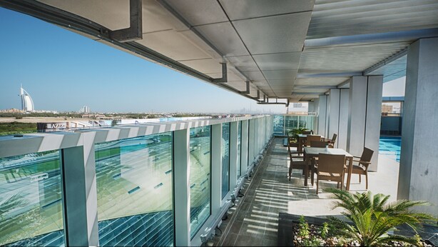 Een balkon met uitzicht op een stadshemelbeeld, een zwembad en terrasmeubilair.