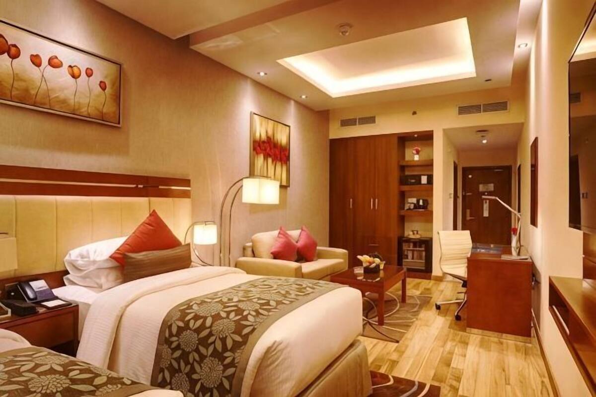 Ein Hotelzimmer mit Bett, Schreibtisch, Sessel, Sofa und Fernseher.