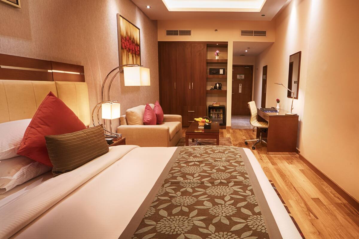 Ein Hotelzimmer mit Bett, Schreibtisch, Stuhl, Lampe und Fernseher.