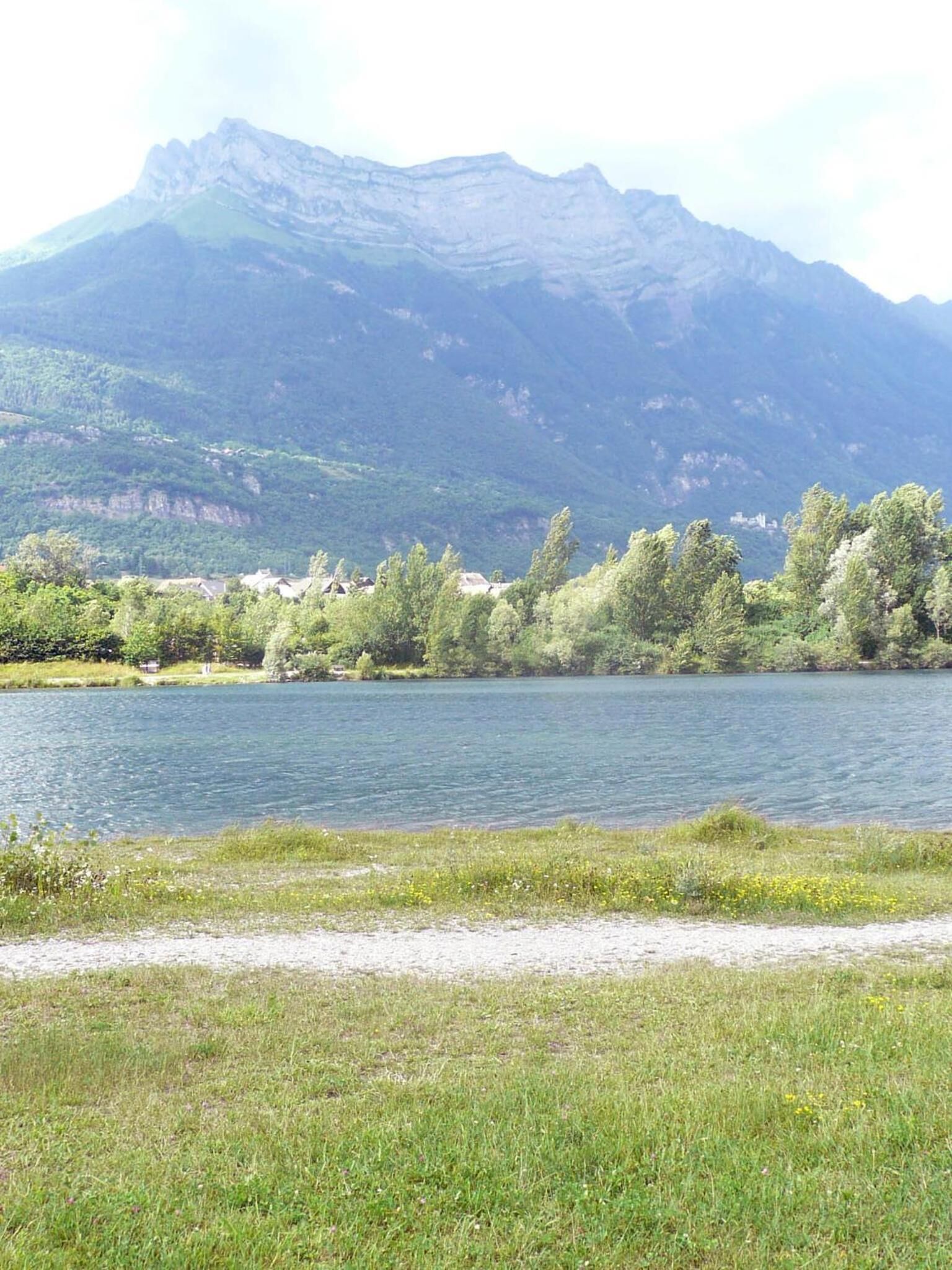 A lake with a mountain in the background and a grassy area in the foreground.