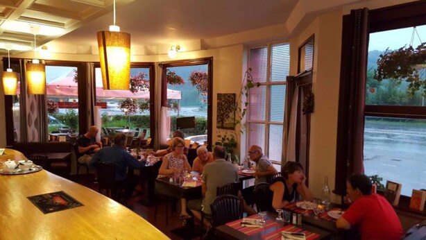 A restaurant with large windows, wooden tables, and hanging lights.