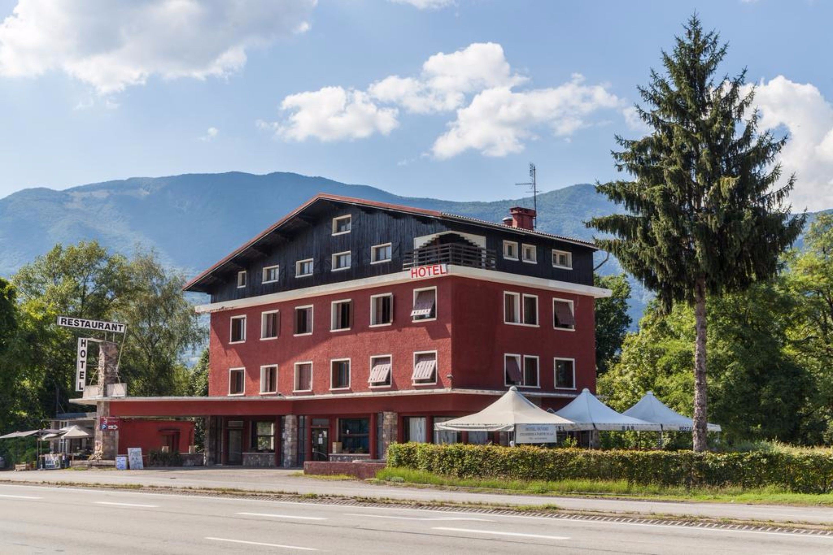 A two-story hotel with a red facade and a sign indicating it is a hotel.
