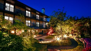 A multi-story hotel with balconies, a landscaped garden, and a koi pond.