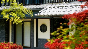 A traditional building with a tiled roof, a stone facade, and a large window with a grid pattern.