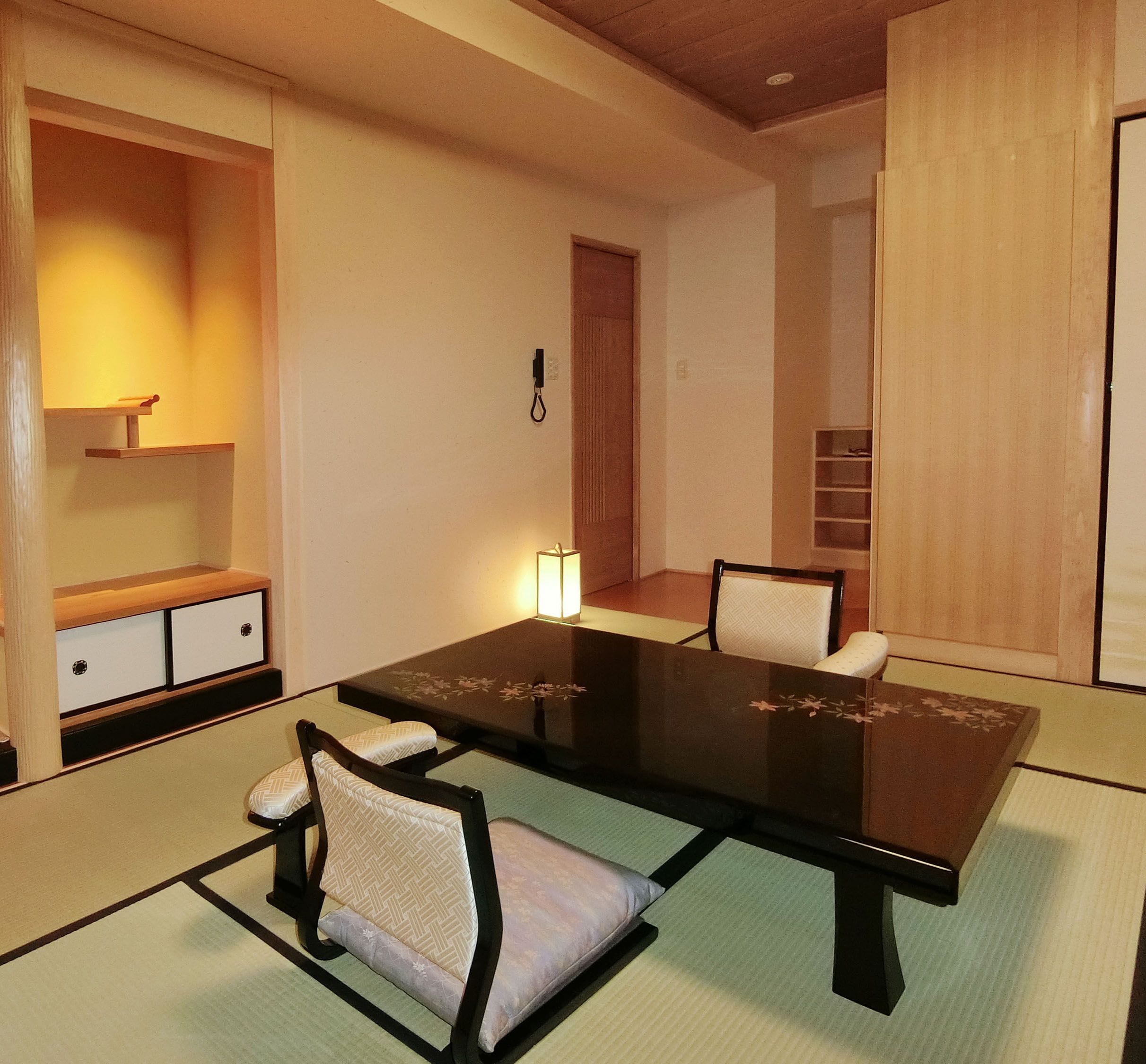 A traditional Japanese-style room with tatami flooring, a low table with cushions, and a sliding door.