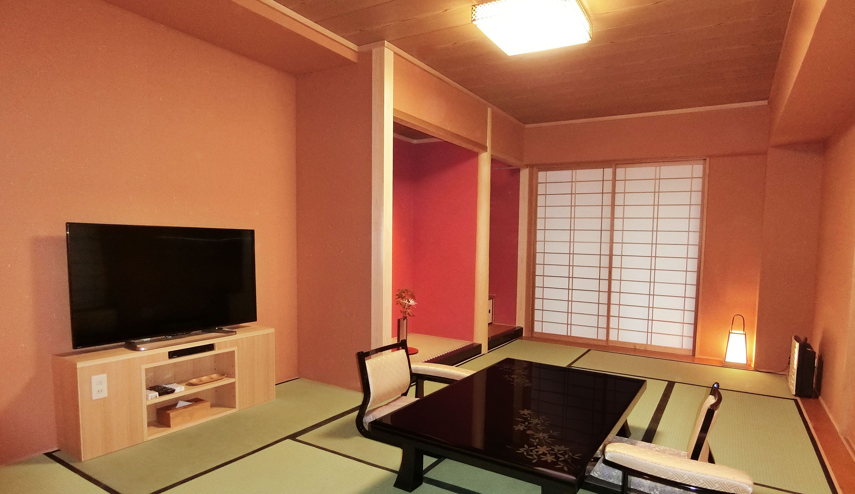 A traditional Japanese-style room with tatami flooring, a low table, and a television on a wooden stand.