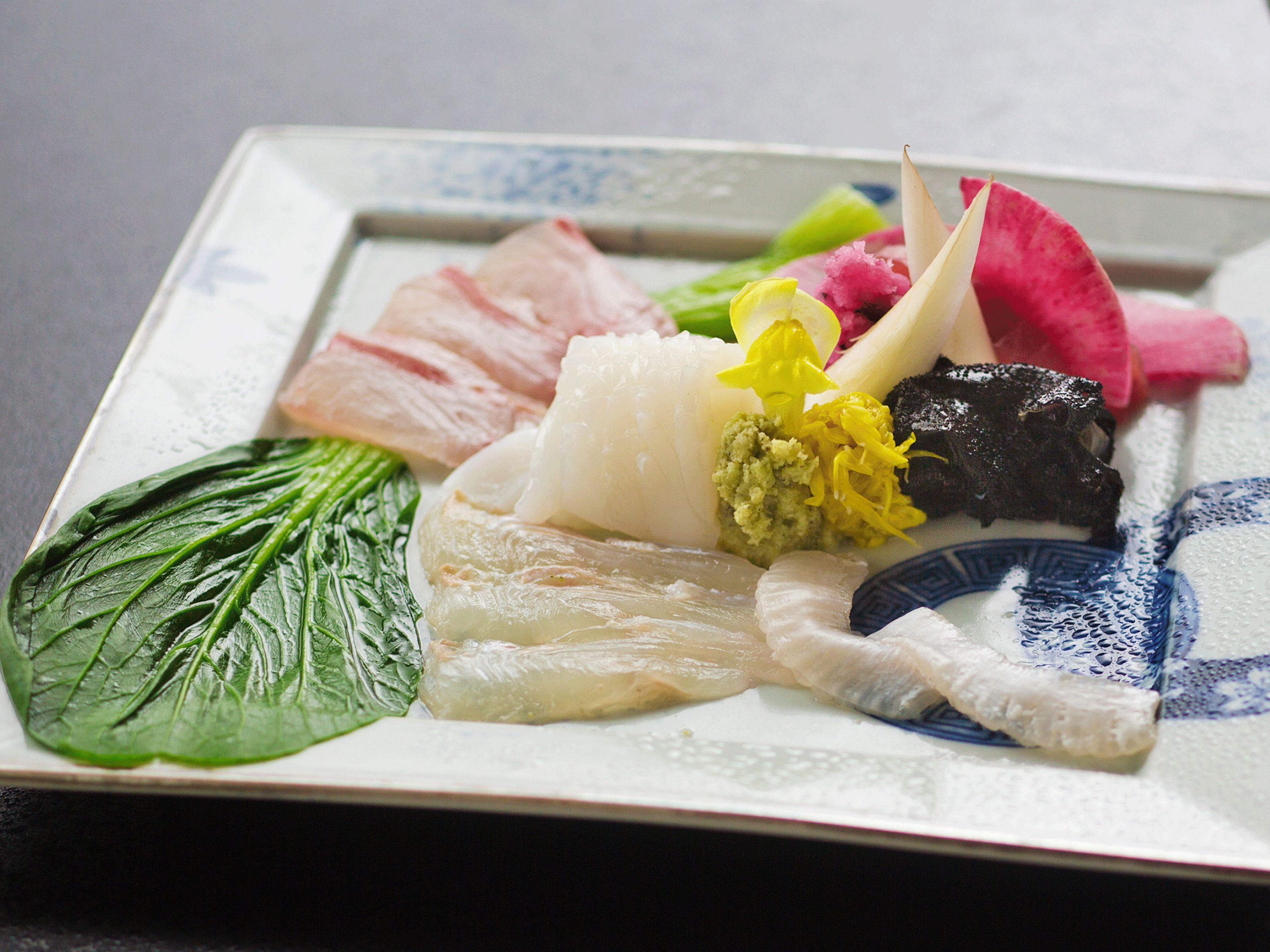 Une assiette de sashimi, composée de différents types de poisson et agrémentée de garnitures.