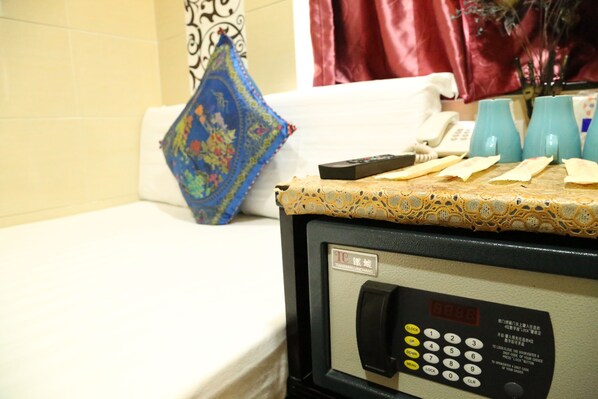 A hotel room with a bed, a small table with a remote control, a phone, and a decorative pillow. - European Hostel (Kowloon)