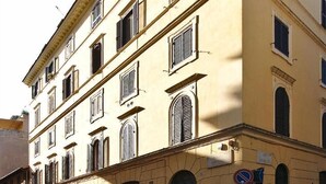 A multi-story building with a yellow facade, multiple windows, and a cobblestone street in front. - B&B Roma Borgo 91 (Rome)