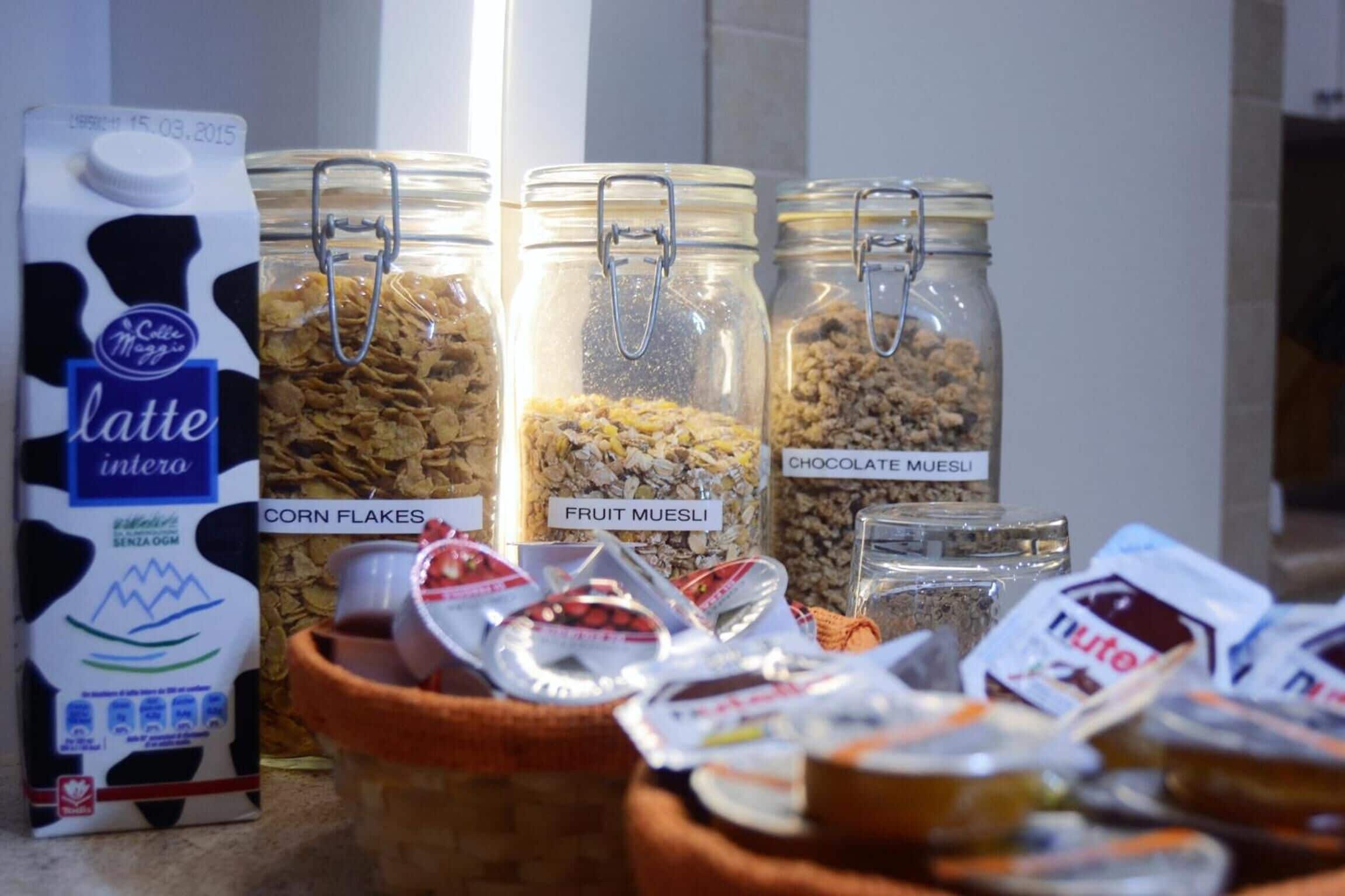 Une variété de produits alimentaires, notamment un carton de lait aromatisé, des céréales de maïs, du muesli aux fruits, du muesli au chocolat et du Nutella.
