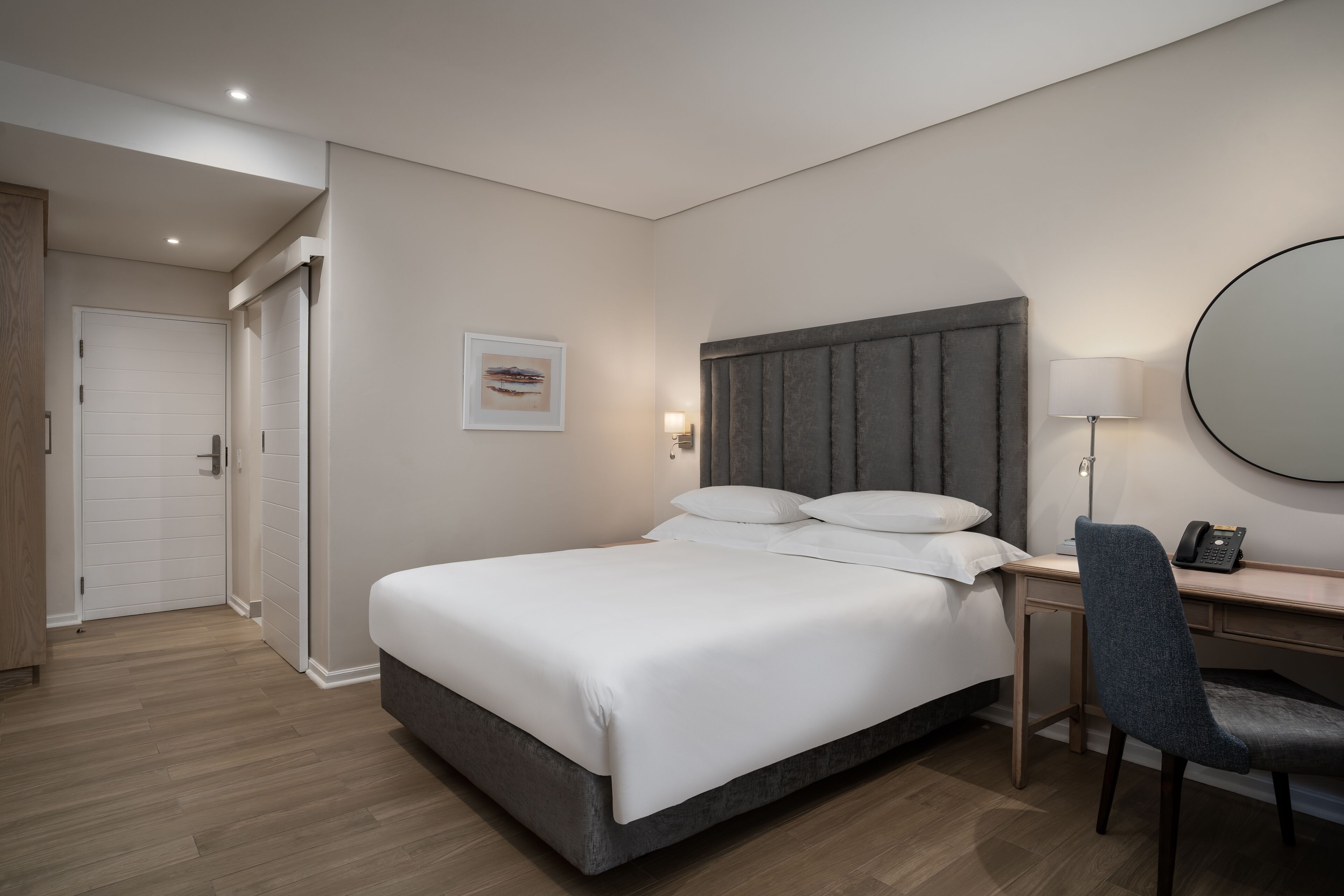 A modern hotel room with a large bed, a desk, and a chair.