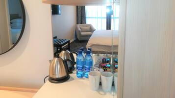 Ein Hotelzimmer mit einem Bett, einer Couch, einer Kaffeemaschine und Wasserflaschen auf dem Tisch.