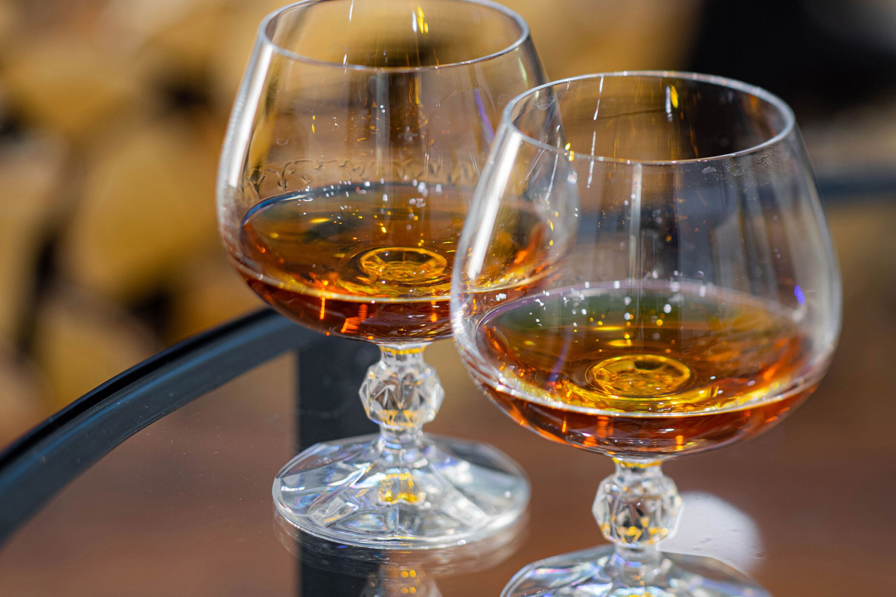 Dos copas de vino de vidrio transparente sobre una superficie reflectante.