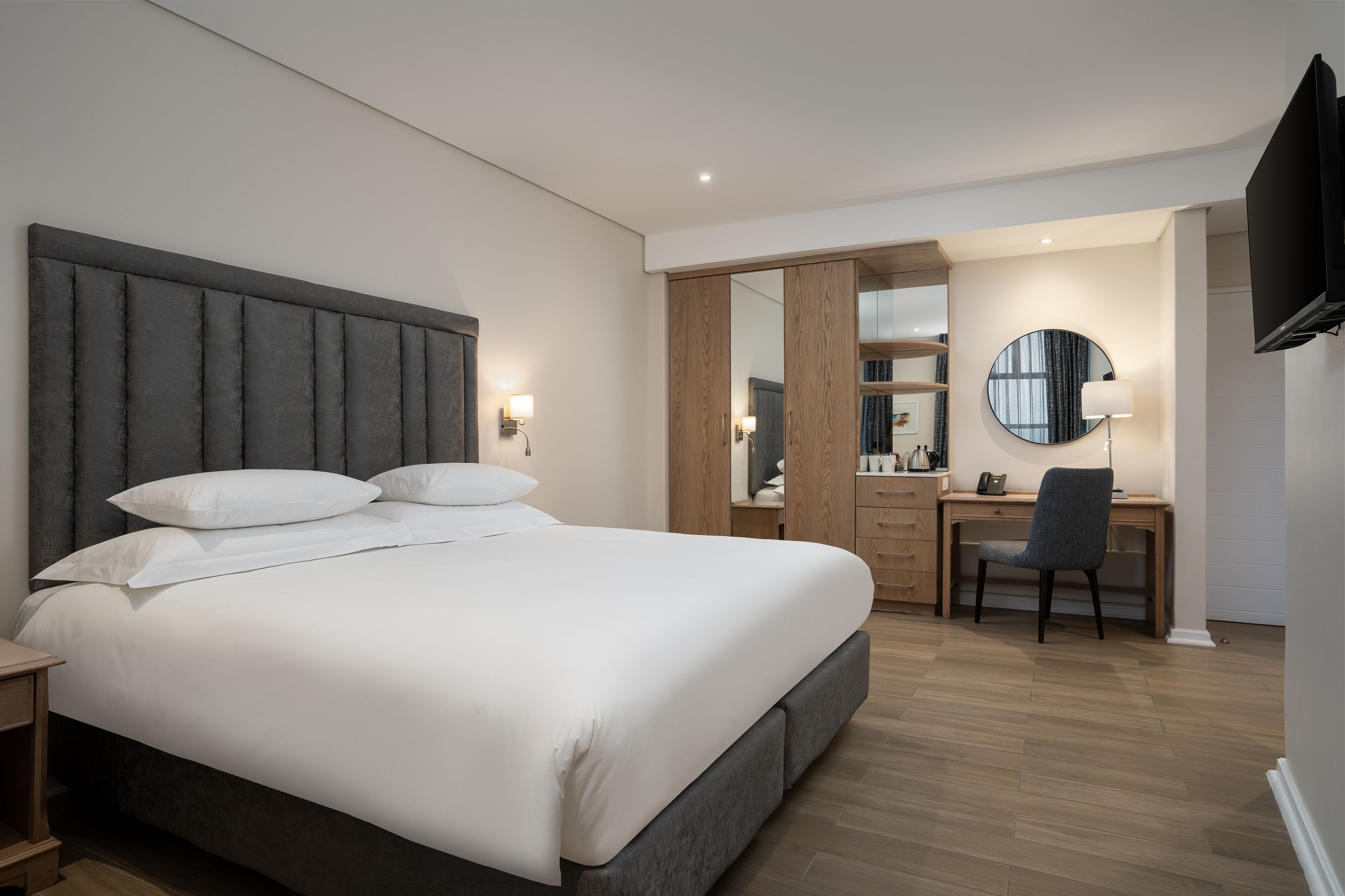 A modern bedroom with a large bed, a desk, and a chair.