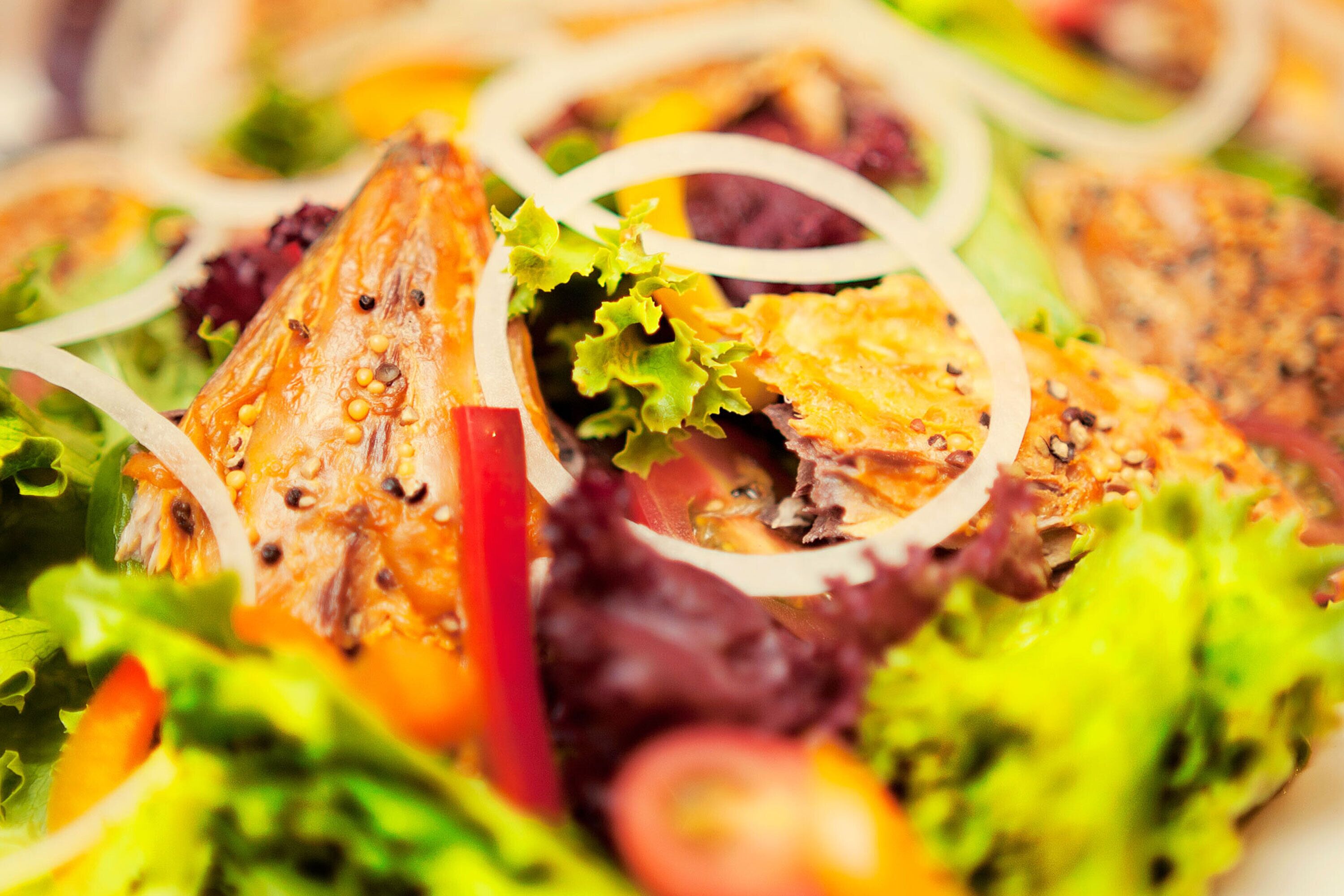 A close-up of a salad with various vegetables and a piece of grilled chicken.