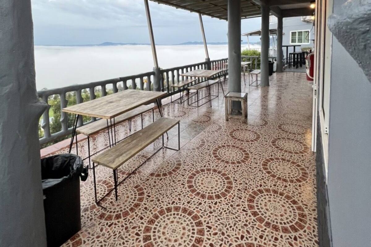 Un espace extérieur abrité, doté d’un sol à motifs, de tables et de bancs, et offrant une vue sur une étendue d’eau.