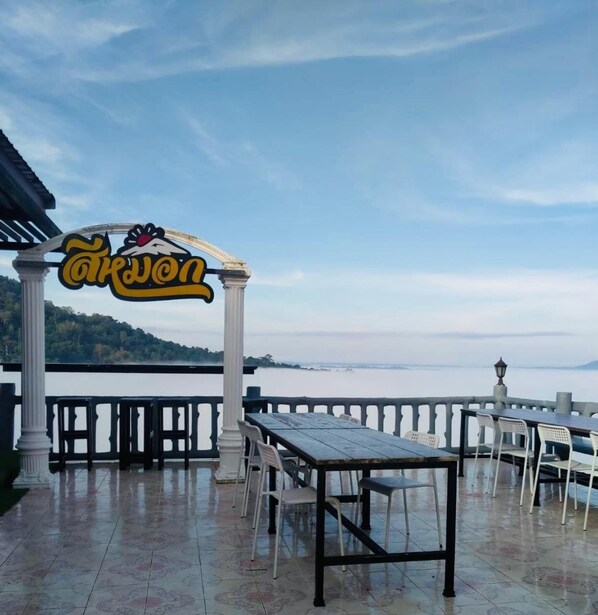 An outdoor dining area with a view of a body of water and hills in the background. - Seemok Resort (Khao Kho)