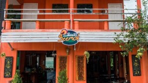 A two-story building with a bright orange facade, a balcony on the upper level, and a sign that reads "Ristorante Seemok." - Seemok Resort (Khao Kho)