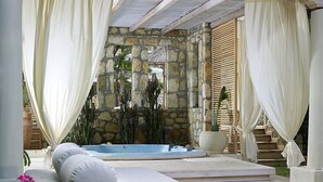 A spa area with a hot tub, a massage table, and a stone wall backdrop. - IridaChic Boutique Hotel & Spa (Hersonissos)