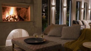 A cozy living room with a fireplace, a sofa, and a coffee table with glasses. - IridaChic Boutique Hotel & Spa (Hersonissos)
