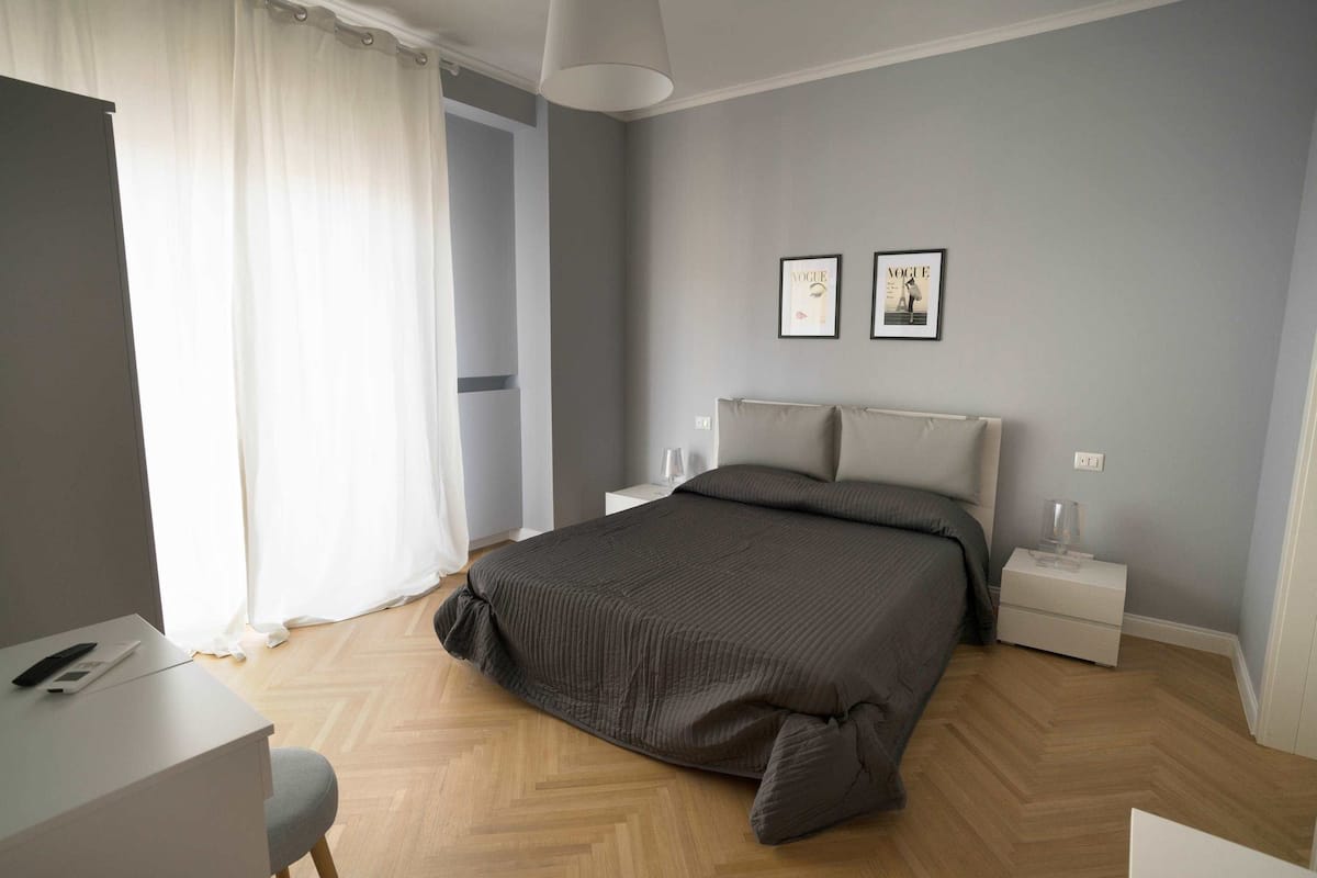 A modern bedroom with a large bed, bedside tables, and a desk.
