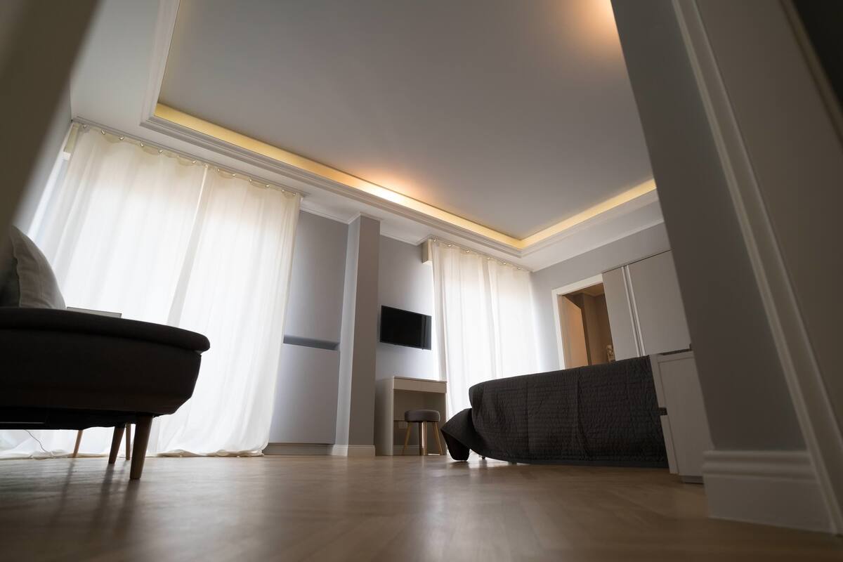 A modern living room with a sofa, a small table, and a TV mounted on the wall.