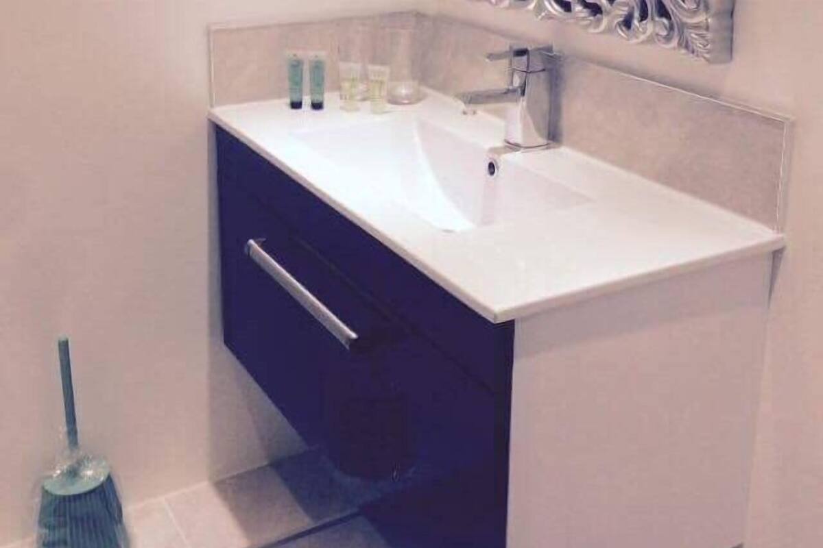 Un baño con un lavabo blanco, un espejo y un armario azul.