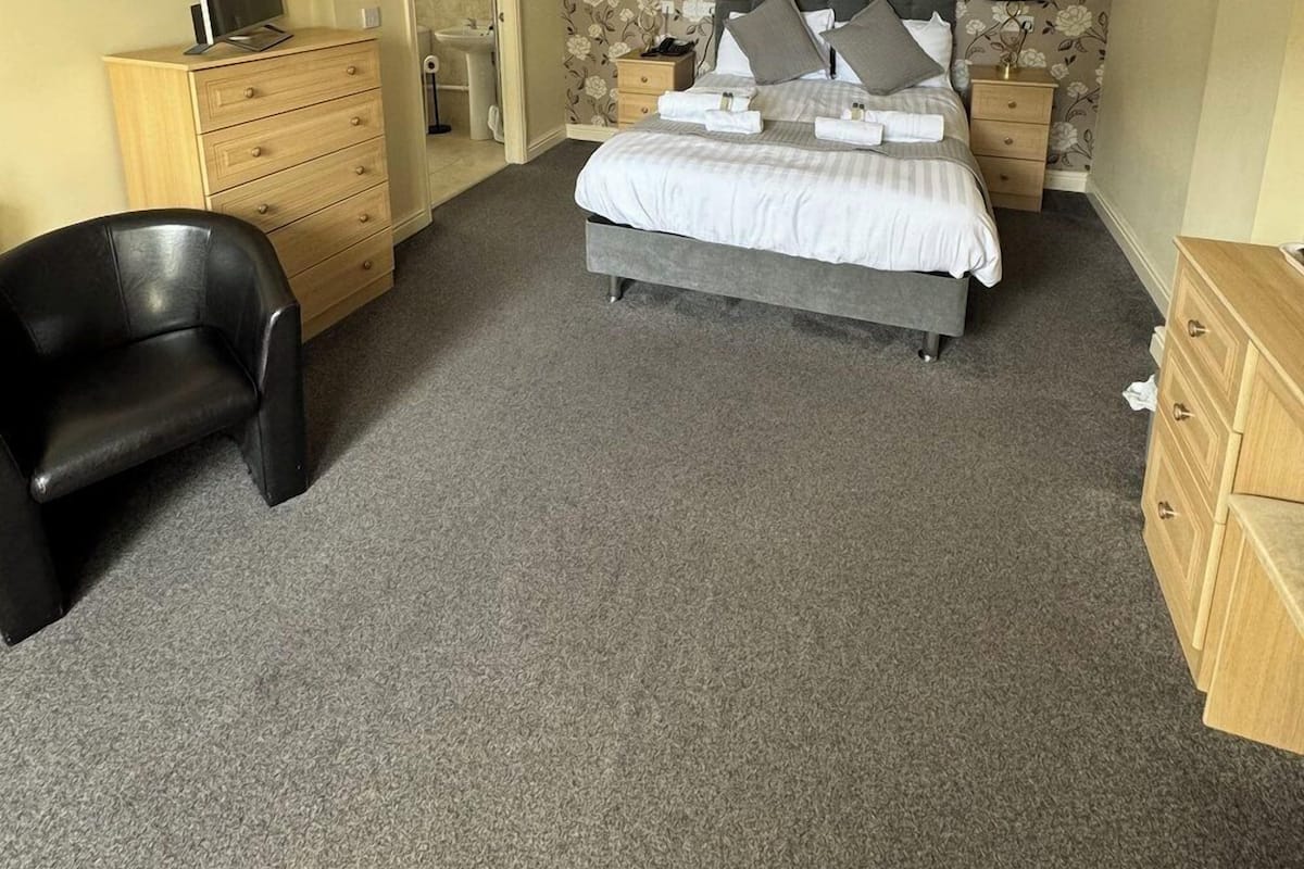 Quarto com cama, escrivaninha, cadeira e cómoda.