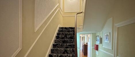 A staircase with patterned carpet and a white handrail leading to a landing.