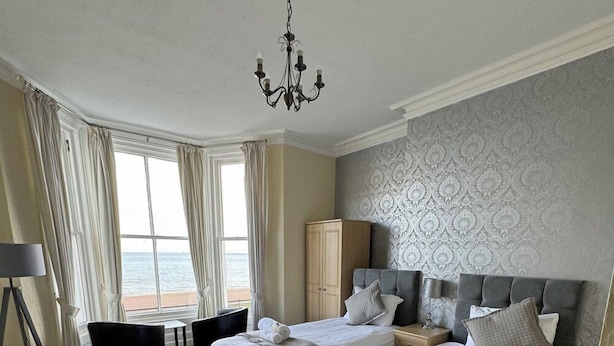 Habitación de hotel con dos camas, un candelabro, vista al mar y una pared con diseño.
