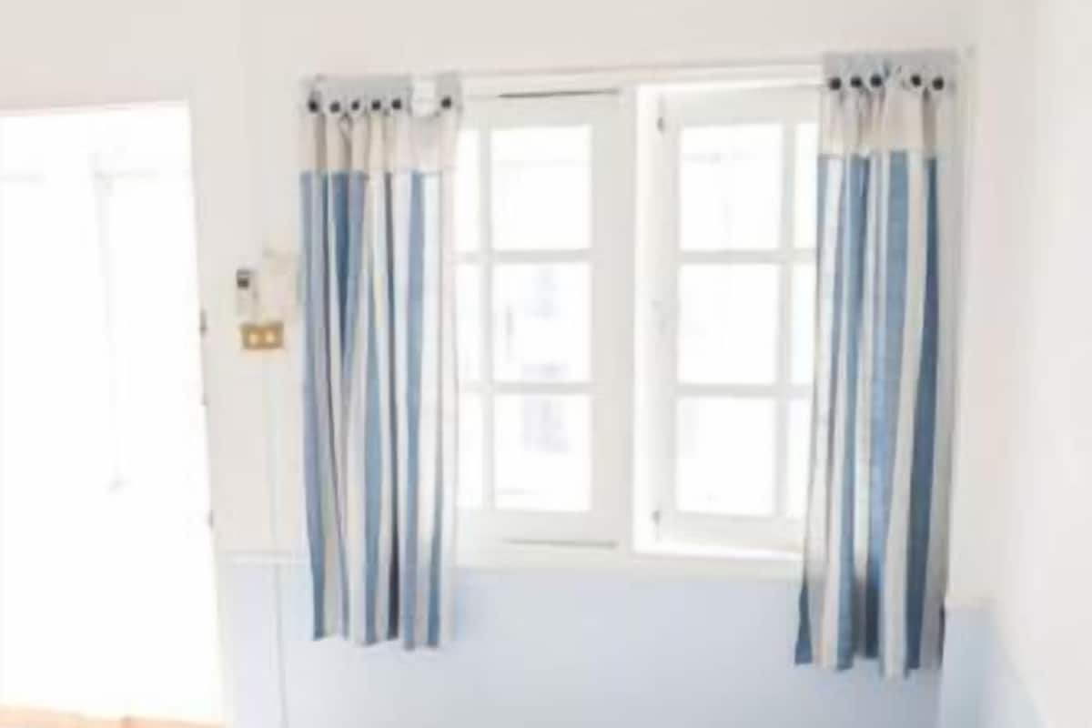 A room with two beds, a window with curtains, and a door.