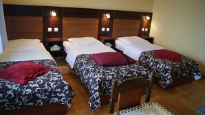 A hotel room with three single beds, each with a wooden headboard and bedside tables. - Domowe Spanie (Lomza)