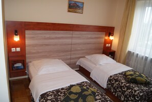 A hotel room with two beds, wooden headboard, bedside lamps, and a painting on the wall. - Domowe Spanie (Lomza)