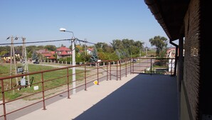 A view from a balcony overlooking a street with a metal railing, a pedestrian path, and houses in the background. - Domowe Spanie (Lomza)