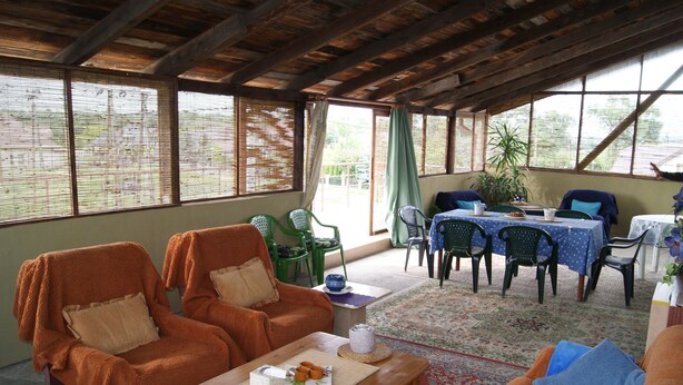 A cozy room with two orange armchairs, a wooden coffee table, and a dining area with a table and chairs. - Domowe Spanie (Lomza)