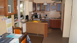 A compact kitchen with wooden cabinets, a central island, and basic appliances. - Domowe Spanie (Lomza)