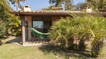 A house with a covered patio, a hammock, and a palm tree.