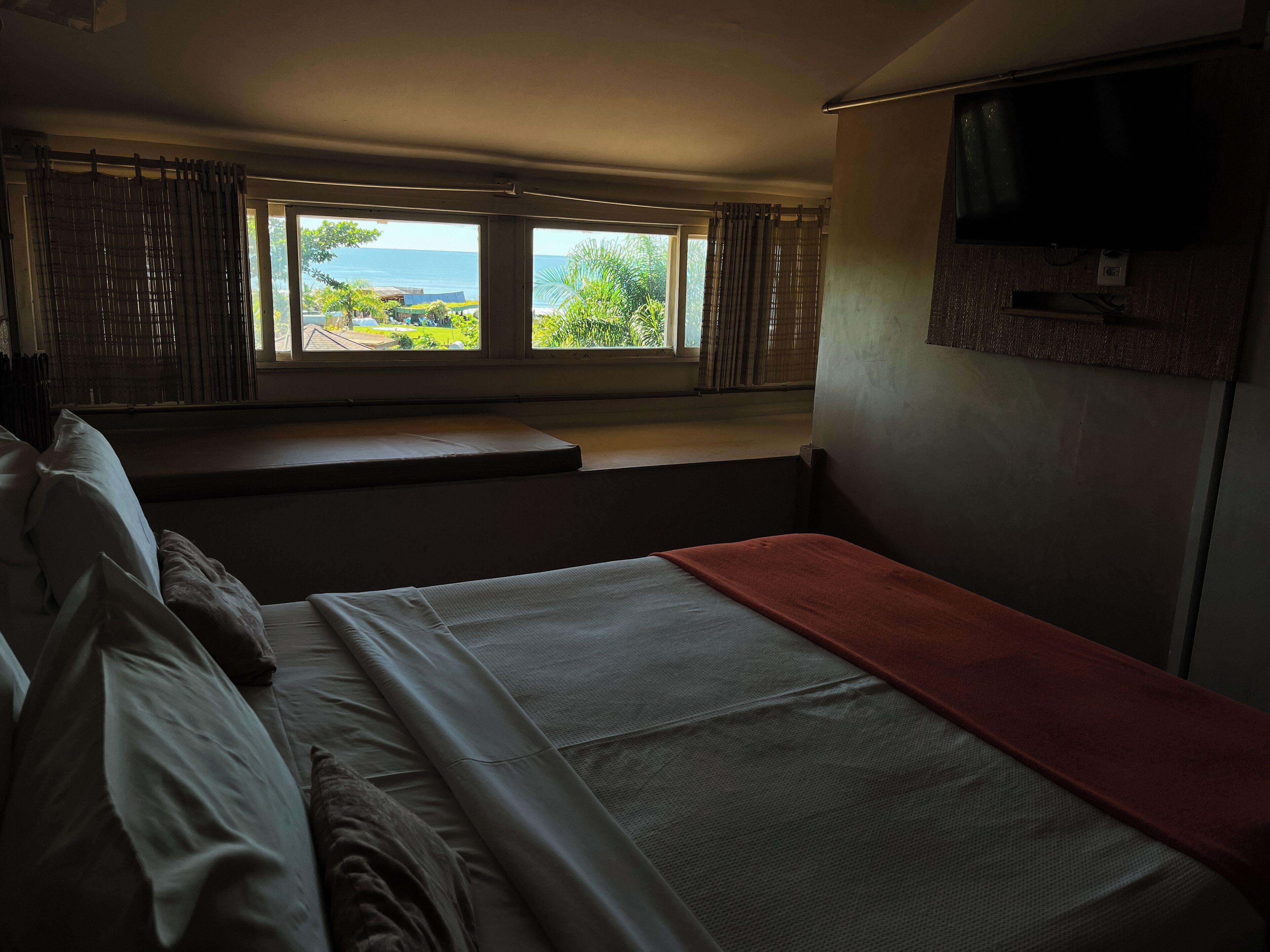 Een kamer met een bed, een bankje en een televisie.