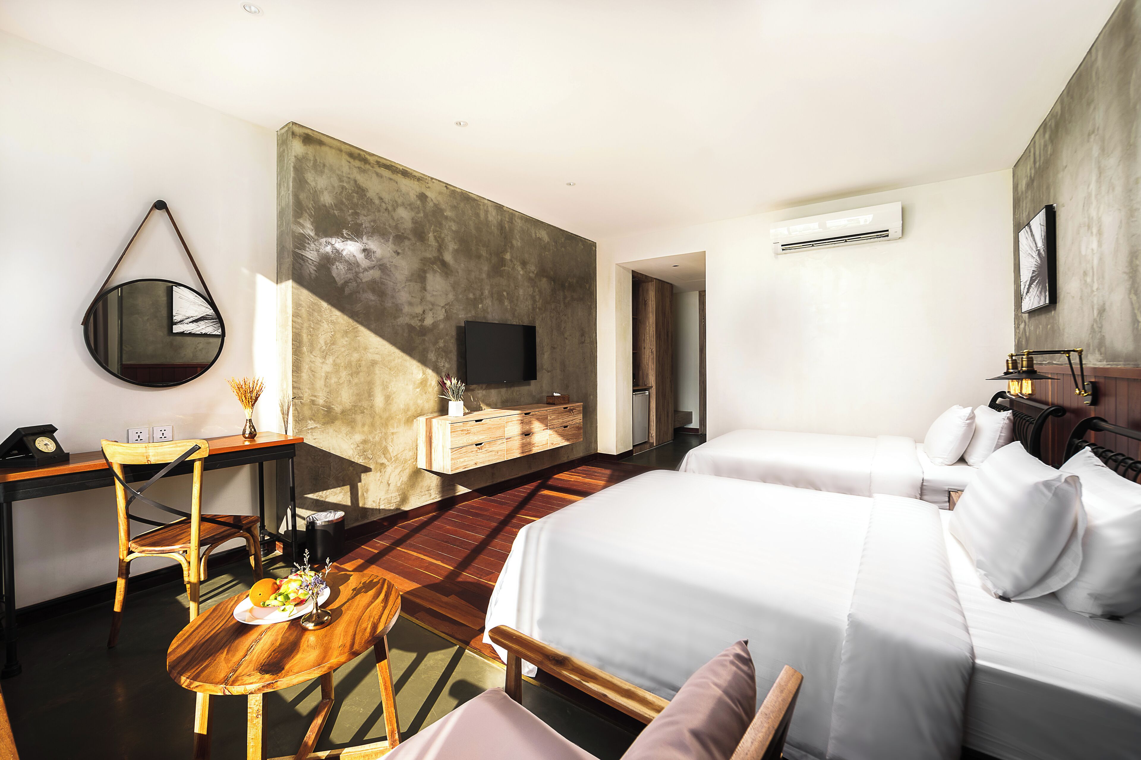A hotel room with a bed, bedside table, chair, desk, and a large mirror.